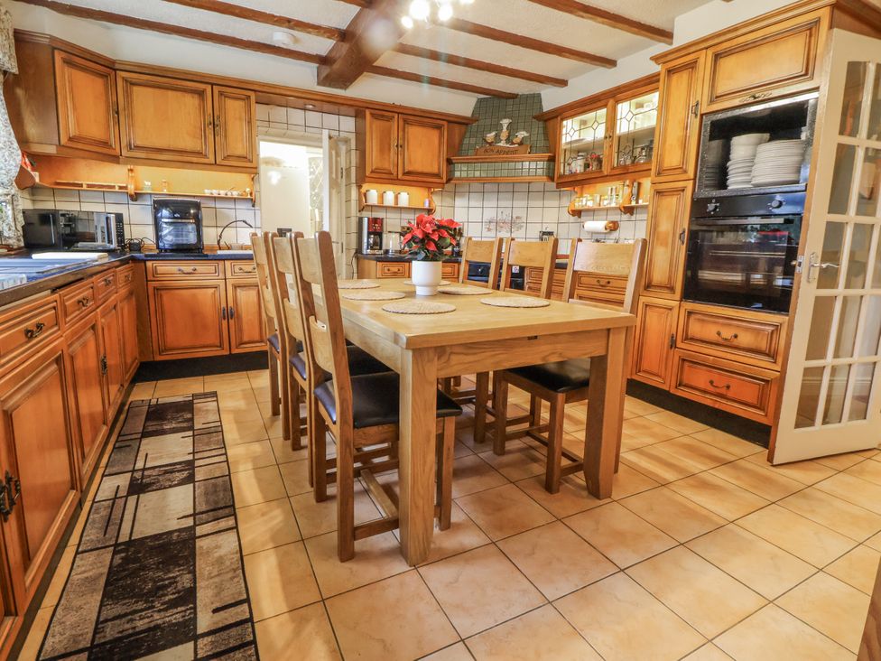 A kitchen with wooden cabinets and a dining table at Freshwinds Market Drayton