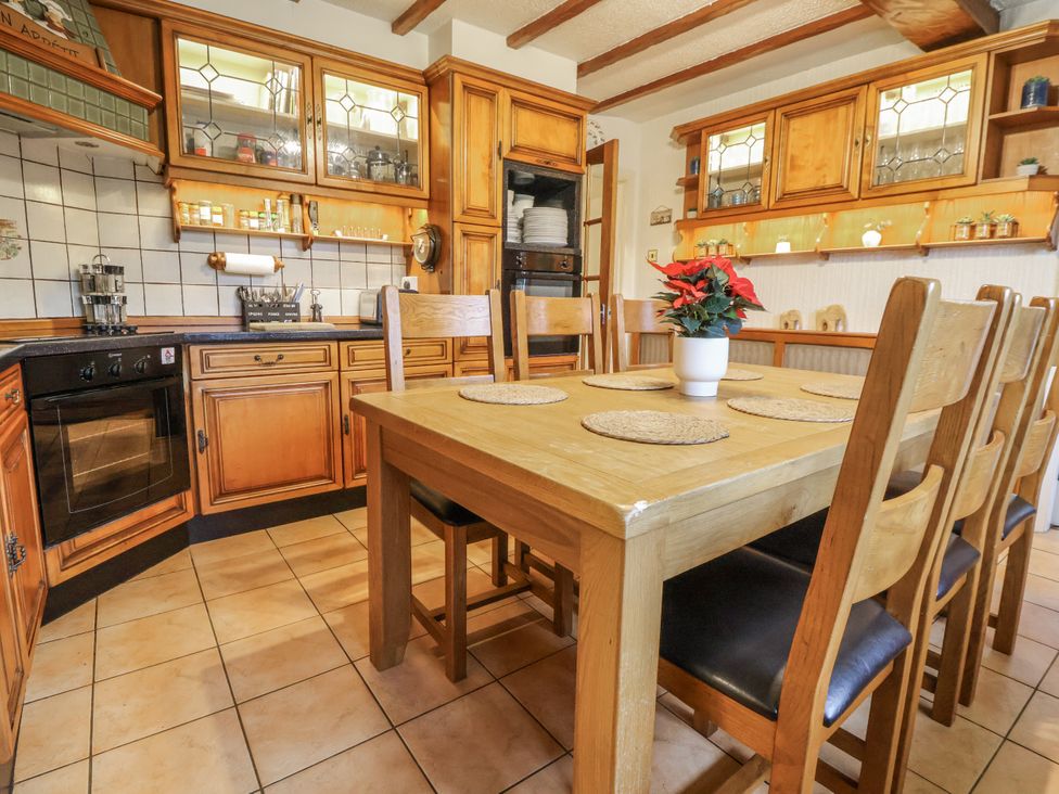 A kitchen with wooden furniture and a dining table at Freshwinds in Market Drayton