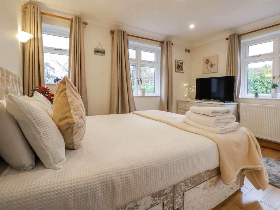 A bedroom with a bed, television, and windows at Freshwinds Market Drayton