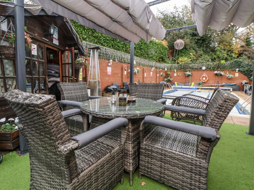 A garden with a dining table and chairs near a pool at Freshwinds in Market Drayton
