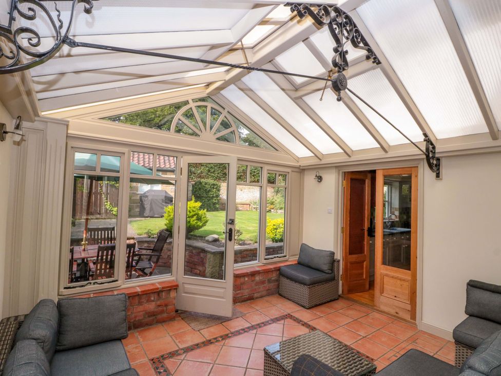 A conservatory with seating and a view of the garden at Weavers Cottage in Carlton-in-Cleveland near Stokesley