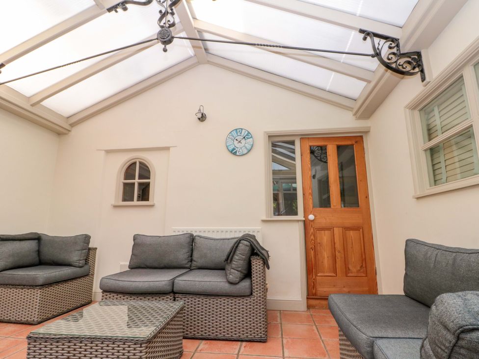 A conservatory with seating and a door at Weavers Cottage Carlton-in-Cleveland near Stokesley