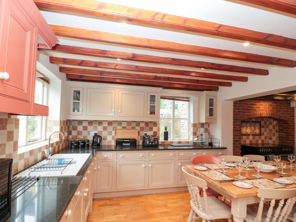 A kitchen with cabinets and dining table at Weavers Cottage in Carlton-in-Cleveland near Stokesley
