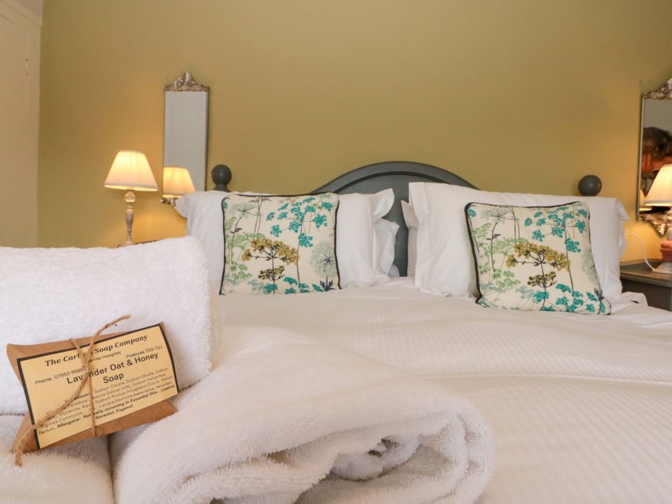 A bedroom with a bed and decorative pillows at Weavers Cottage in Carlton-in-Cleveland near Stokesley