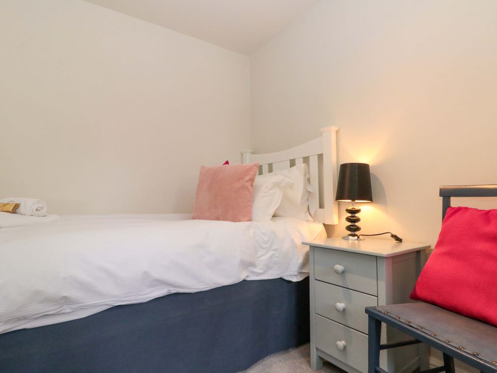 A bedroom with a bed, nightstand, lamp, and chair at Weavers Cottage, Carlton-in-Cleveland near Stokesley