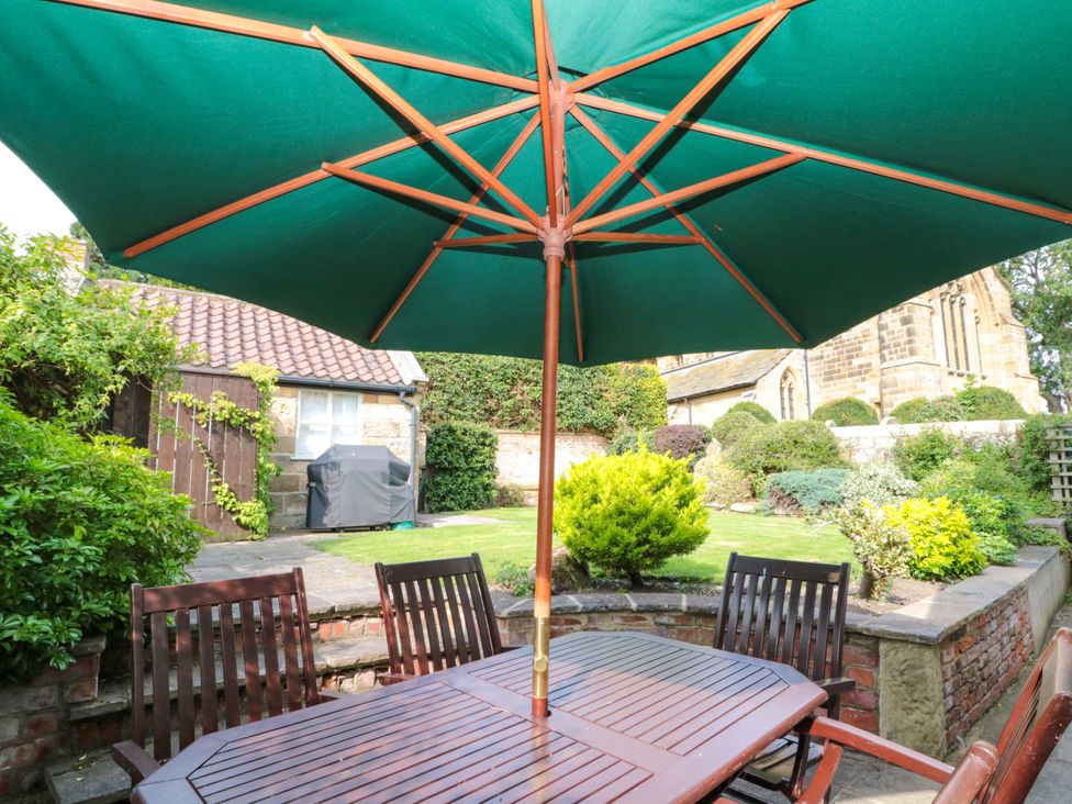 A garden with a table and chairs under an umbrella at Weavers Cottage in Carlton-in-Cleveland near Stokesley