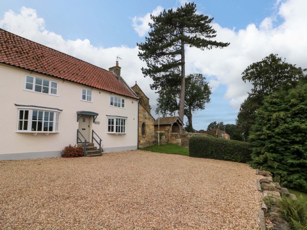 A house with a gravel driveway and trees at Weavers Cottage in Carlton-in-Cleveland near Stokesley