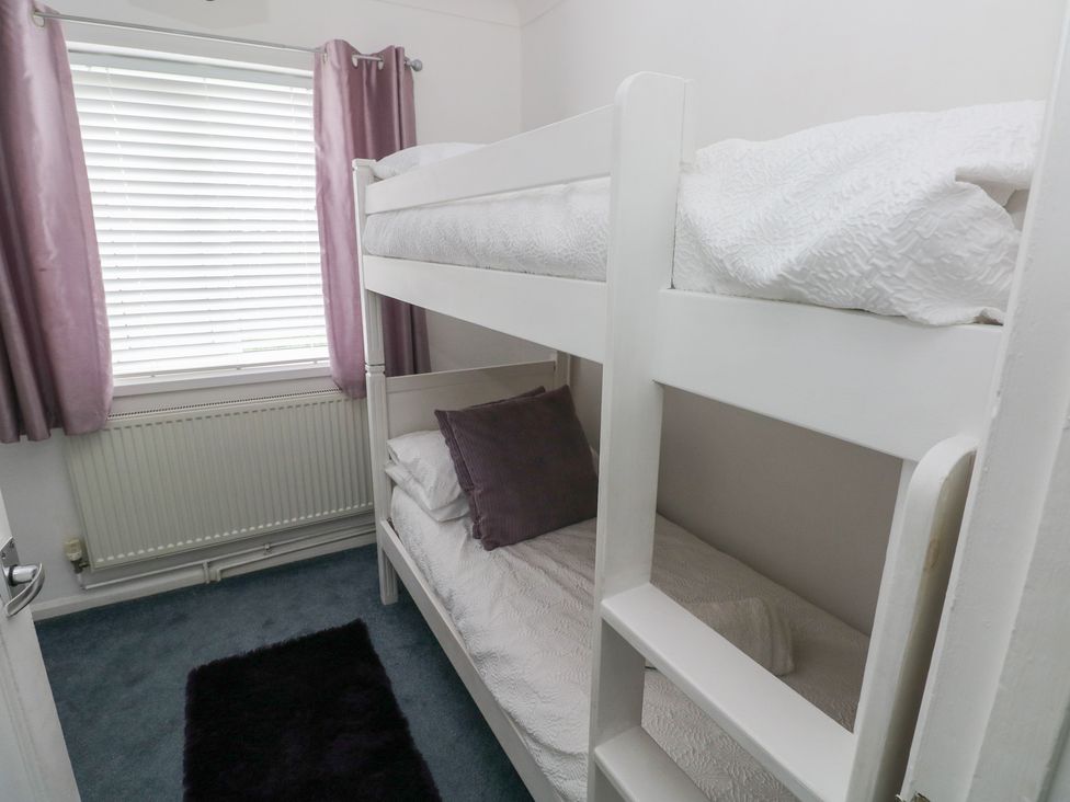 A bedroom with a bunk bed and curtains at Cwtch Ar Y Mor Burry Port