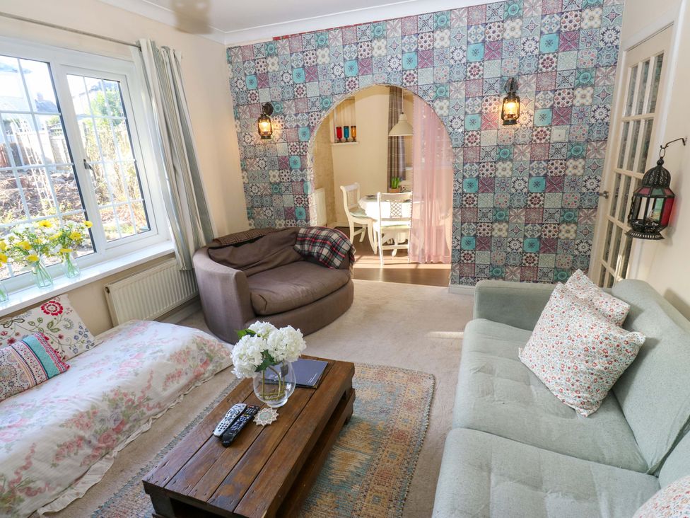 A living room with a sofa and a table at Hira's Cottage