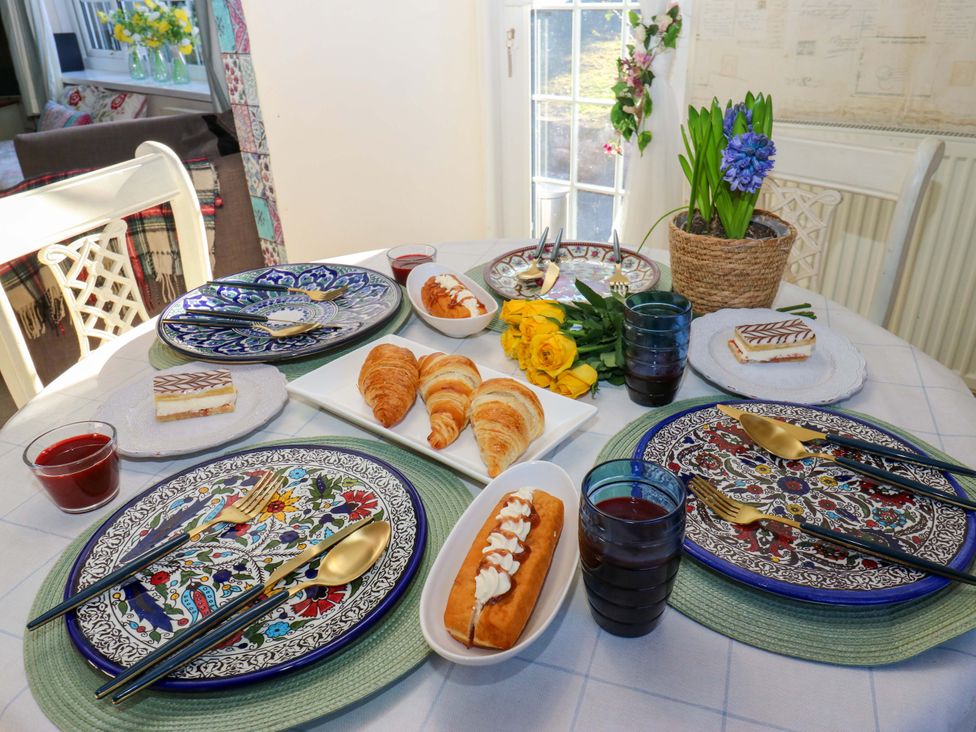 A dining table set with plates and food at Hira's Cottage