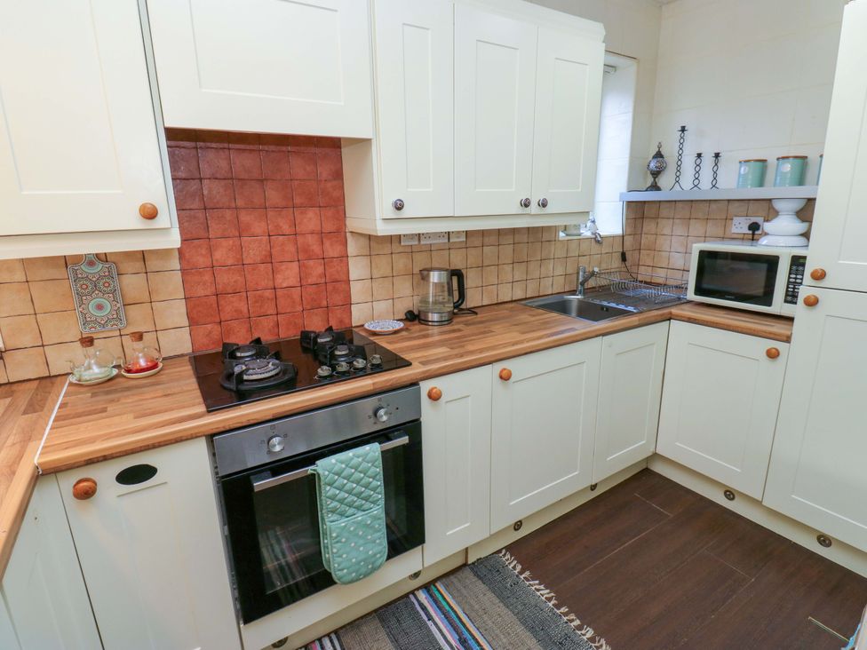 A kitchen with a stove, oven, sink, and microwave at Hira's Cottage