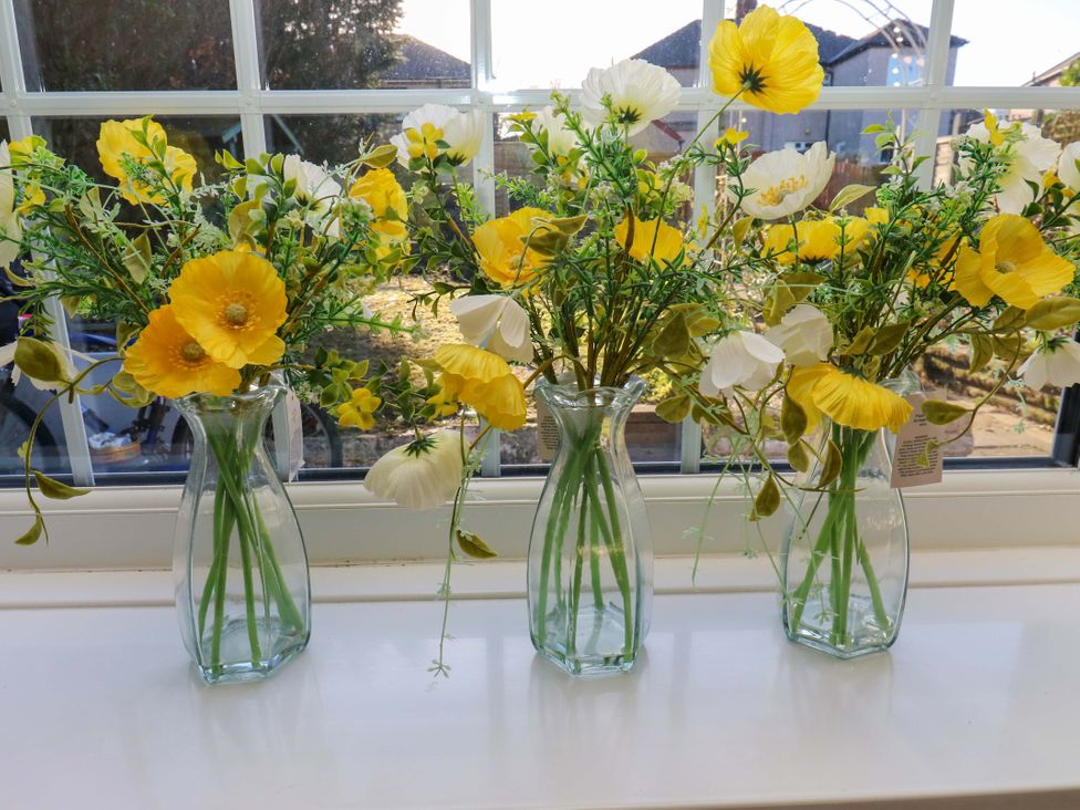Three vases with flowers on a windowsill at Hira's Cottage