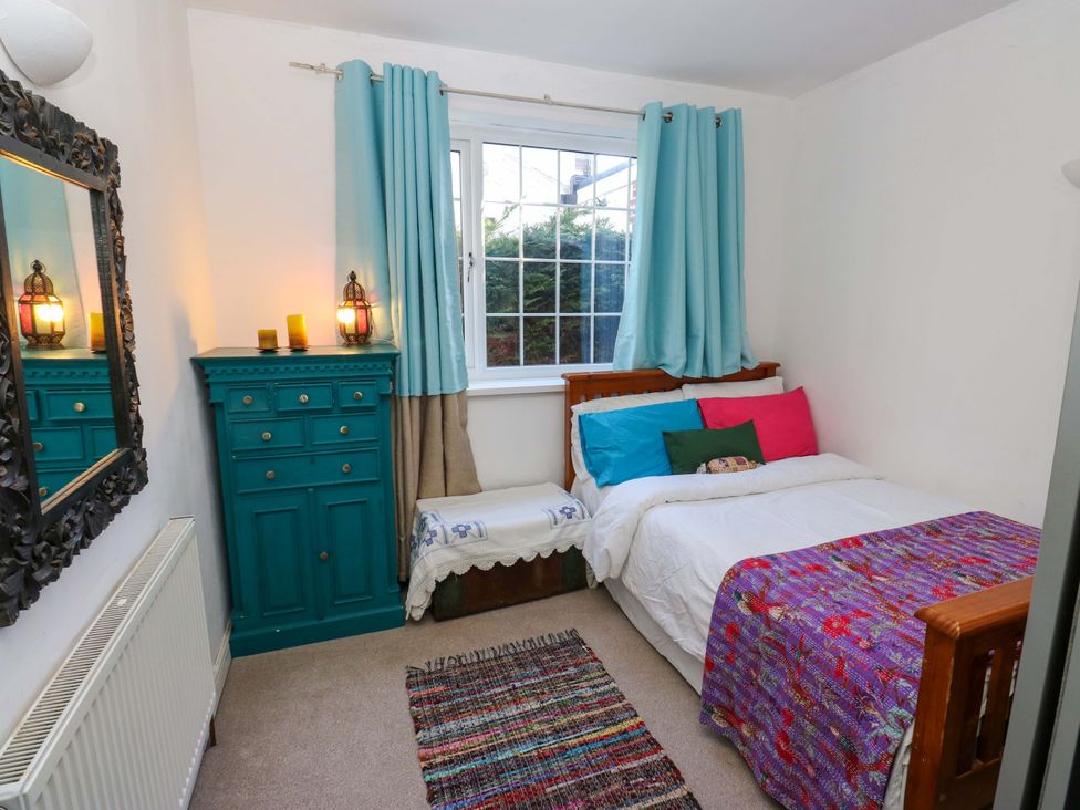 A bedroom with bed, dresser, and mirror at Hira's Cottage