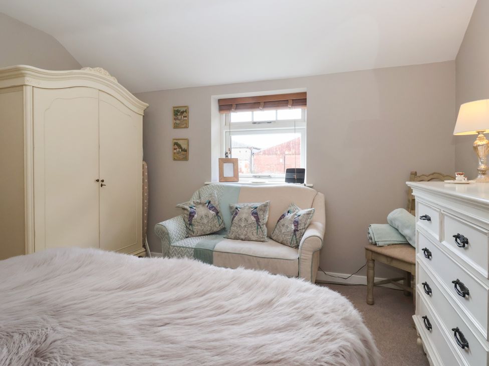 A bedroom with a wardrobe, sofa and bedside table at 1 Church Barns Pocklington