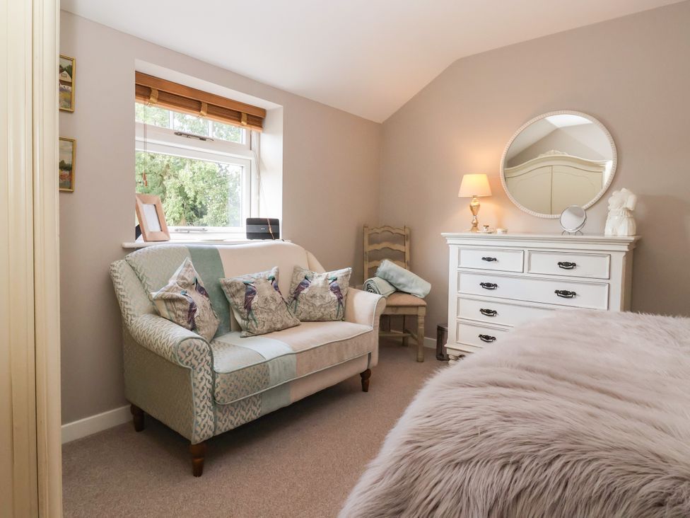 A bedroom with a sofa, dressing table and bed at 1 Church Barns in Pocklington