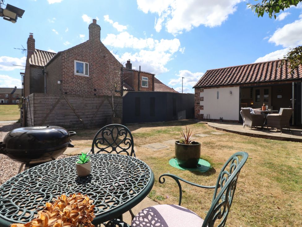 A garden with a table, chairs, and a grill at 1 Church Barns Pocklington
