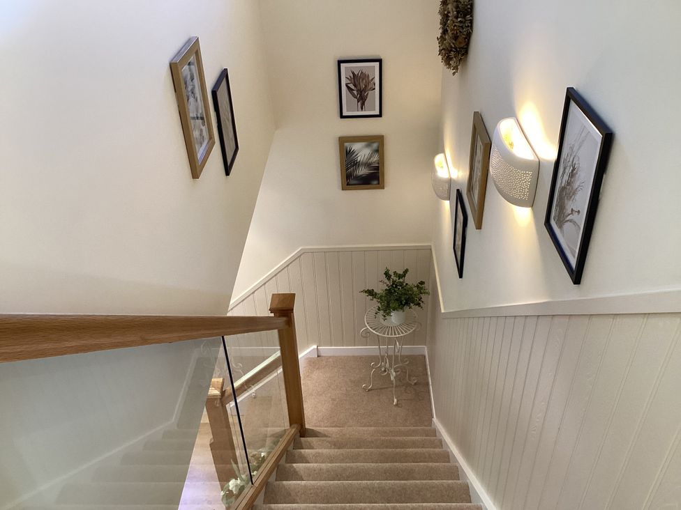 A staircase with framed pictures and a decorative plant at Larchwood Lodge in Ellon