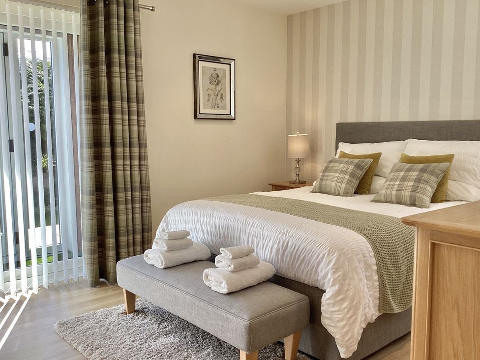 A bedroom with a bed and bedside table at Larchwood Lodge in Ellon
