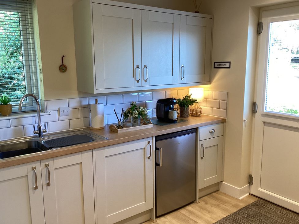A kitchen with a sink, cabinets, refrigerator and coffee maker at Larchwood Lodge in Ellon