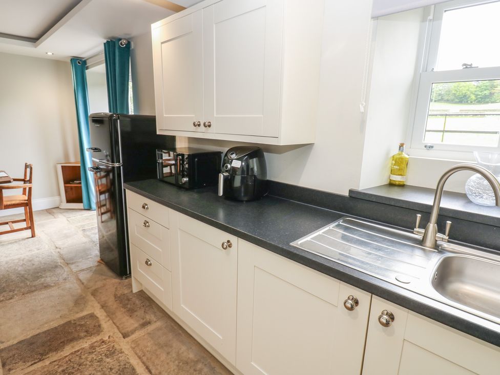 A kitchen with appliances and wooden table at White Lea in Reeth