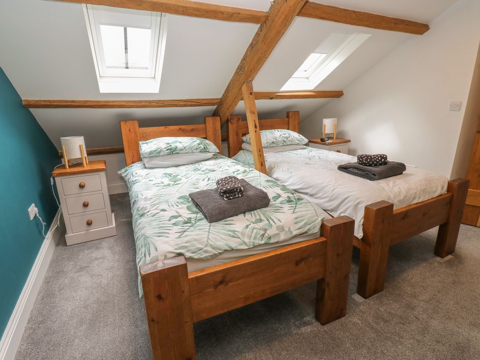 A bedroom with two beds and a bedside table at White Lea in Reeth