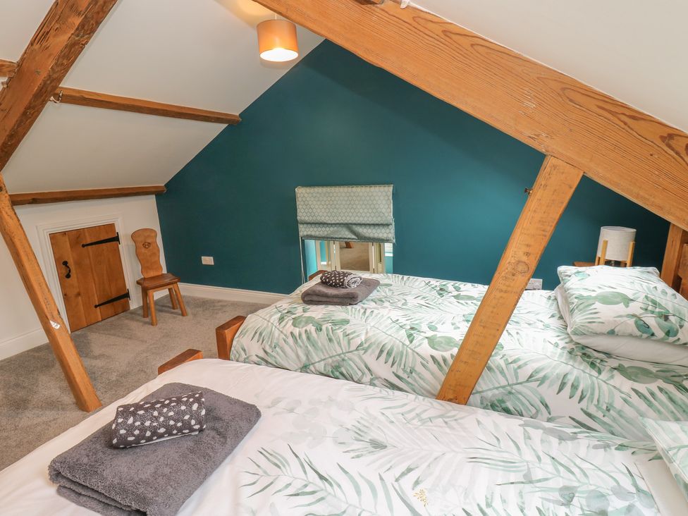 A bedroom with beds and wooden beams at White Lea in Reeth