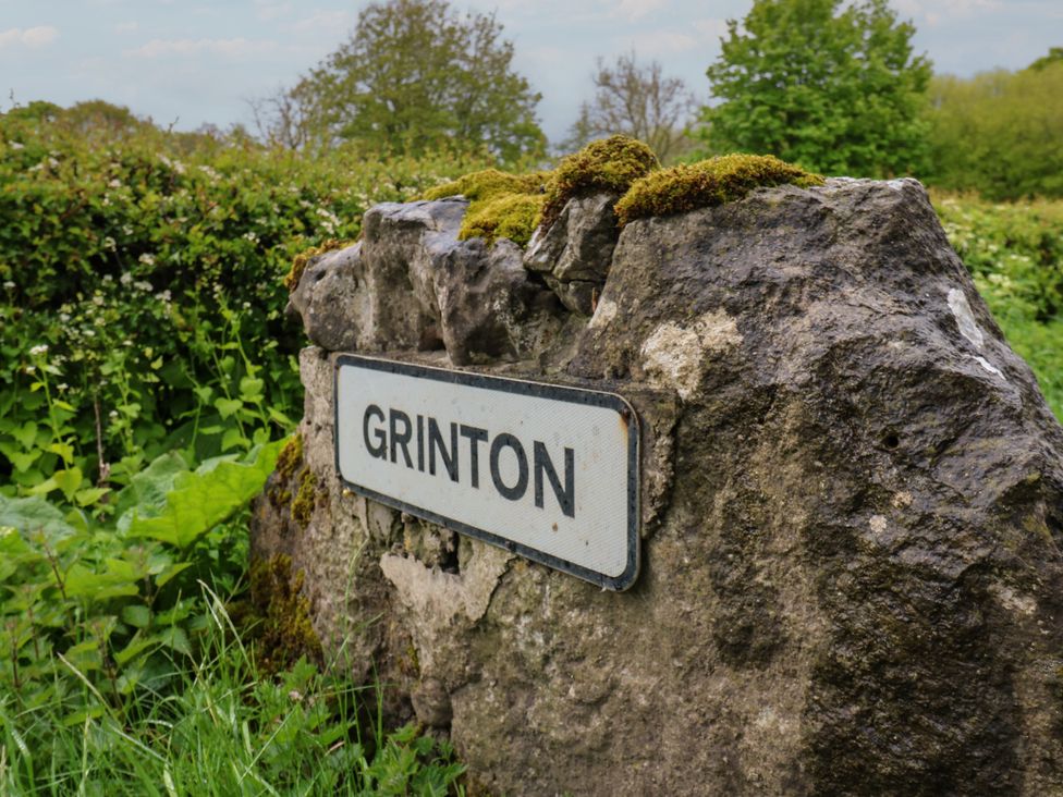 A sign reading Grinton in a green area at White Lea in Reeth