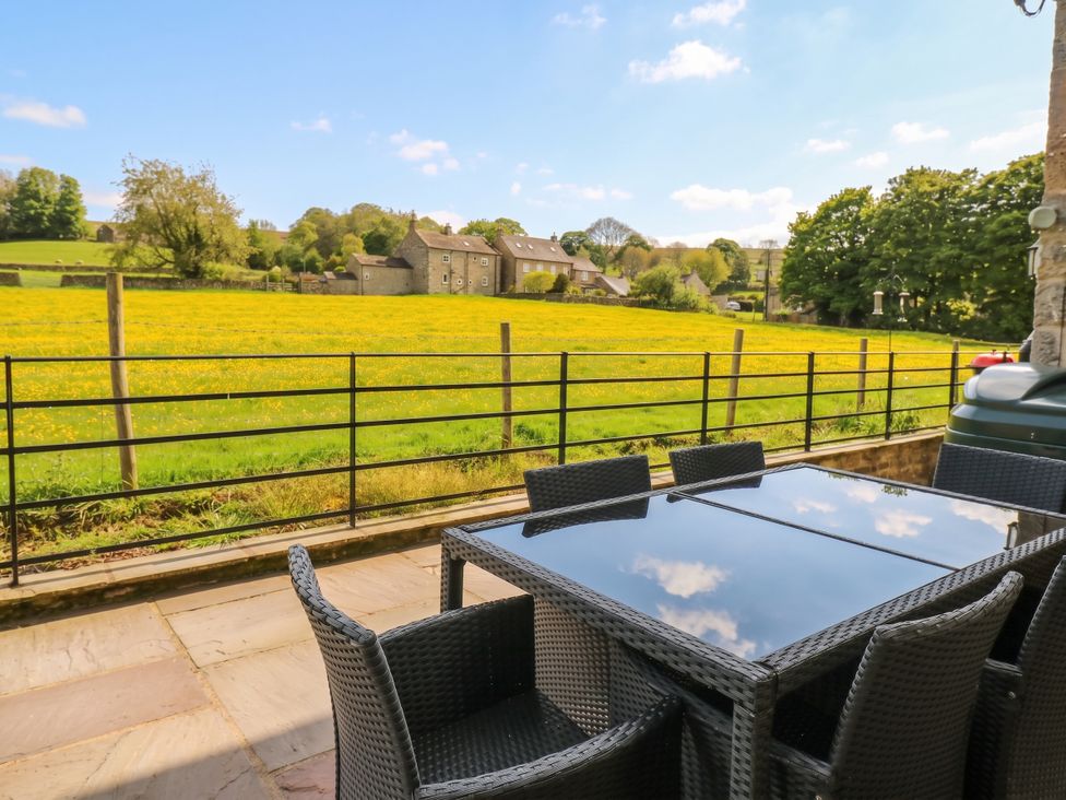 An outdoor patio with a table and chairs overlooking a field at White Lea in Reeth