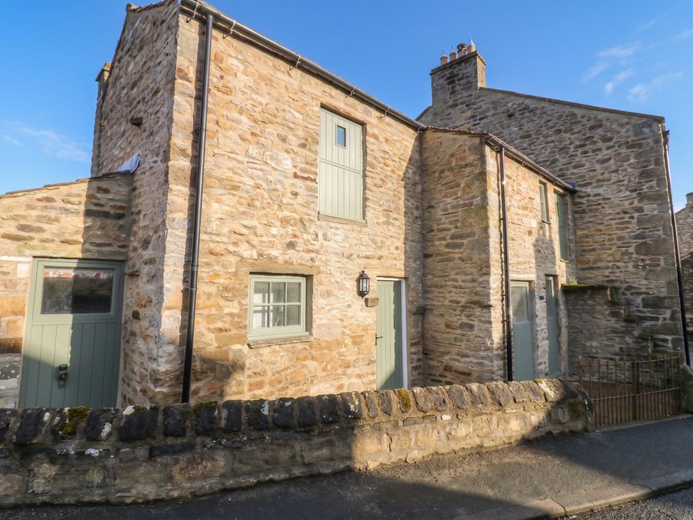 A stone cottage exterior with a wall at White Lea in Reeth