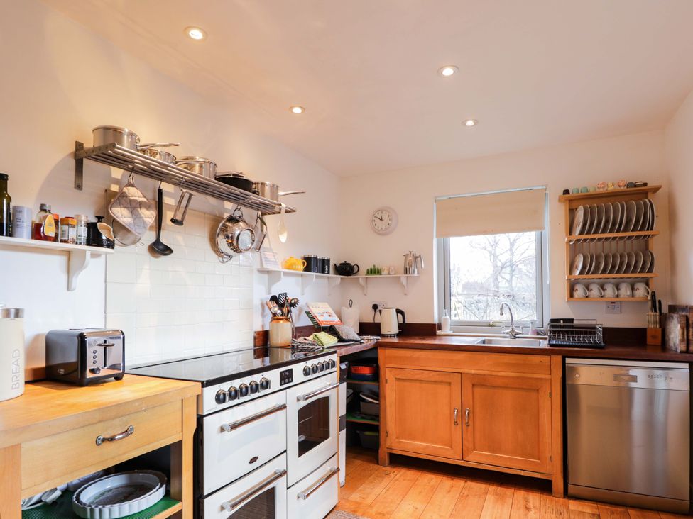 A kitchen with an oven, sink, and shelves of dishes at Inshcraig in Kincraig near Aviemore