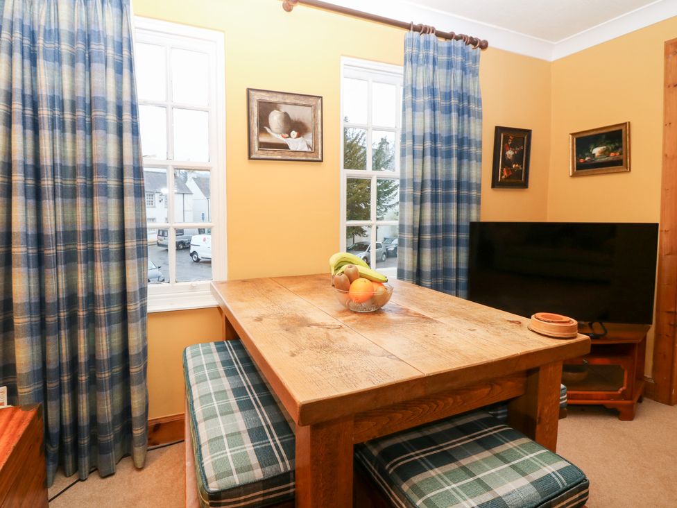 A dining room with a table, chairs, and a television at 1 The Cross in Dunkeld