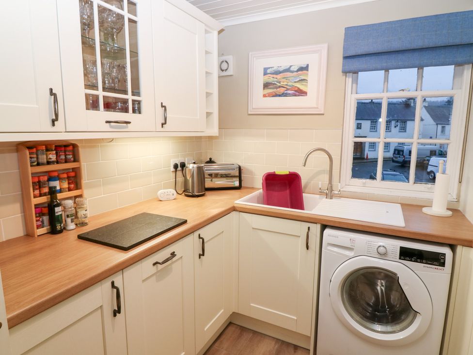 A kitchen with a sink, washing machine, and spice rack at 1 The Cross in Dunkeld