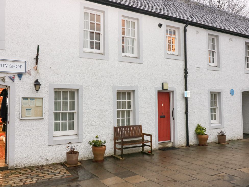 An outdoor view of a charity shop with a red door at 1 The Cross Dunkeld
