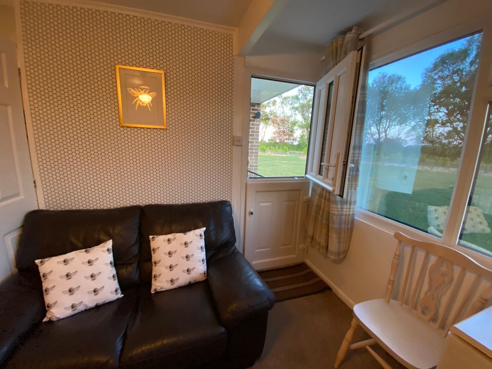 A snug room with a sofa, cushions, and a window at 246 California Road, California, Norfolk