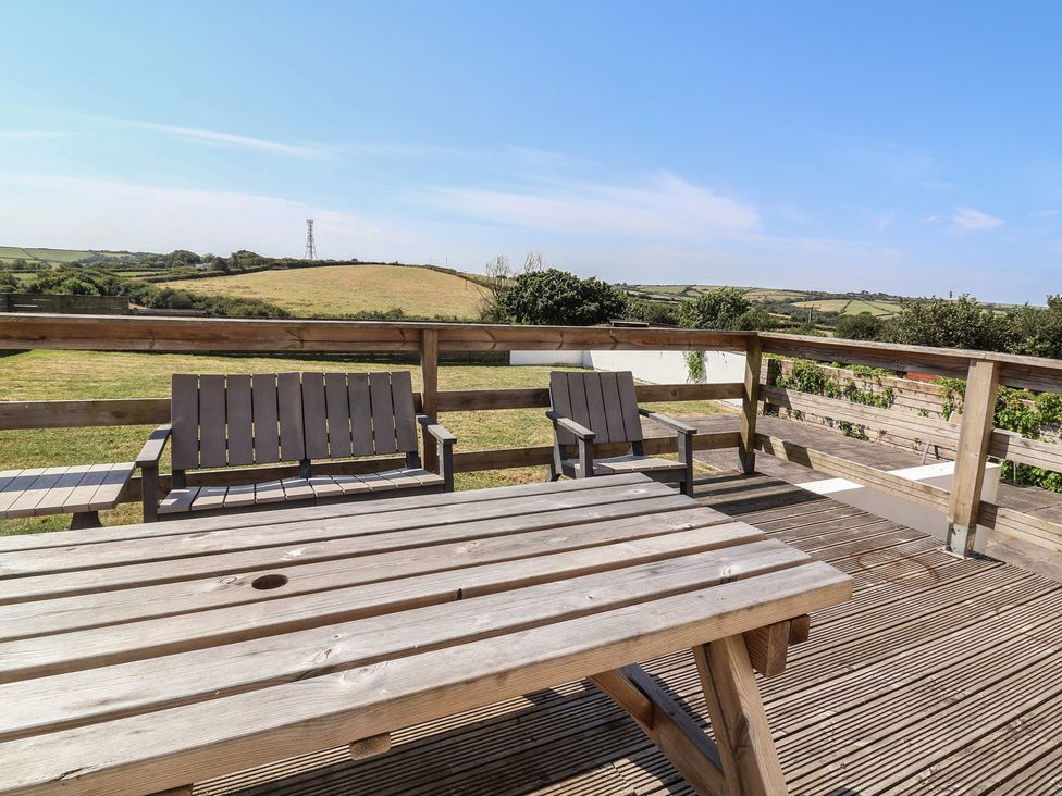 An outdoor area with wooden table and chairs at Auverne Poundstock near Widemouth Bay