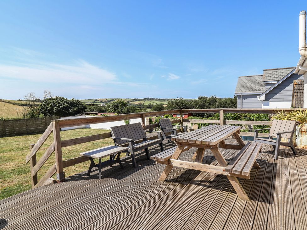 An outdoor seating area with a table and chairs at Auverne Poundstock near Widemouth Bay