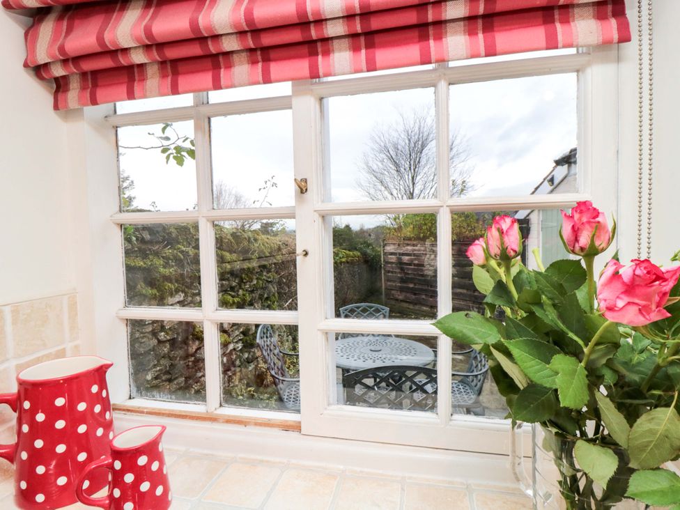 A kitchen window with roses and a view of a table in the garden at Beacon Cottage in Pickering
