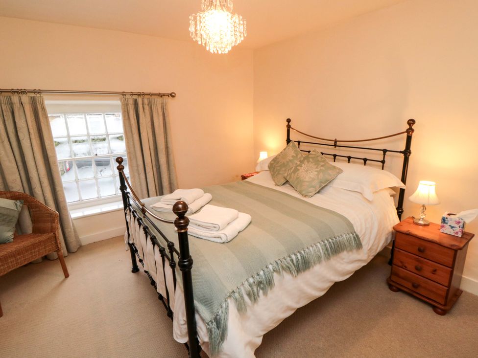 A bedroom with a bed and a chair at Beacon Cottage in Pickering