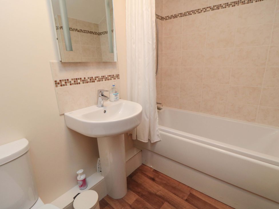 A bathroom with a toilet, wash basin, and bathtub at Beacon Cottage in Pickering