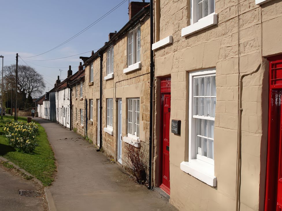 A row of houses with red doors and white windows at Beacon Cottage in Pickering