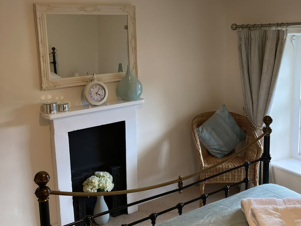 A bedroom with a bed and a mirror at Beacon Cottage in Pickering