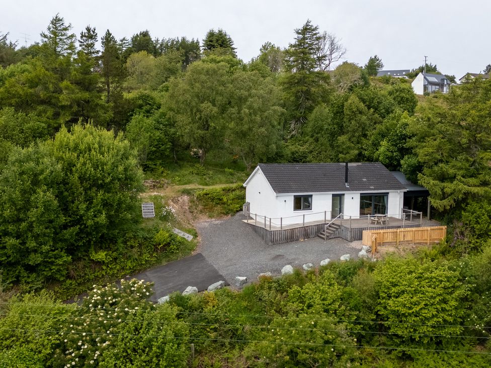 A white house with a gray roof surrounded by trees and greenery at The Lookout in Saasaig near Broadford