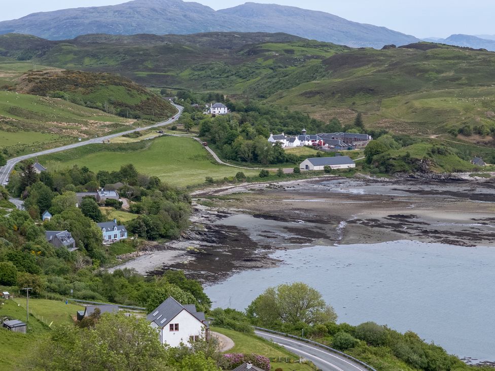 A coastal landscape with houses along a road and a shoreline with hills in the background at The Lookout in Saasaig near Broadford