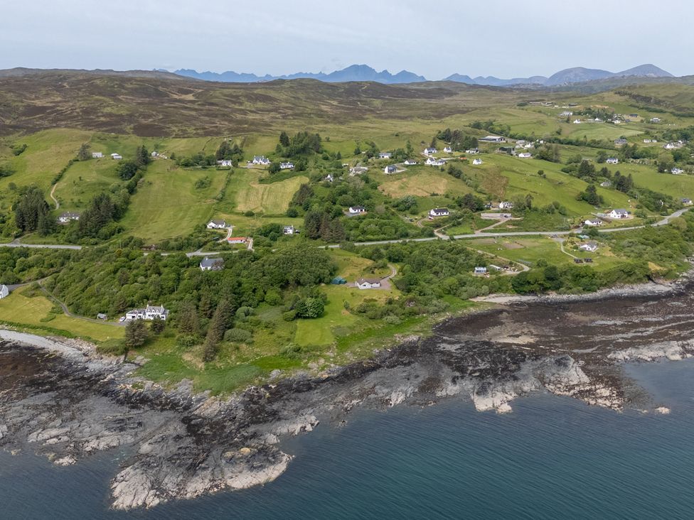 A rural coastal area with houses scattered across green hills and rocky shoreline at The Lookout in Saasaig near Broadford