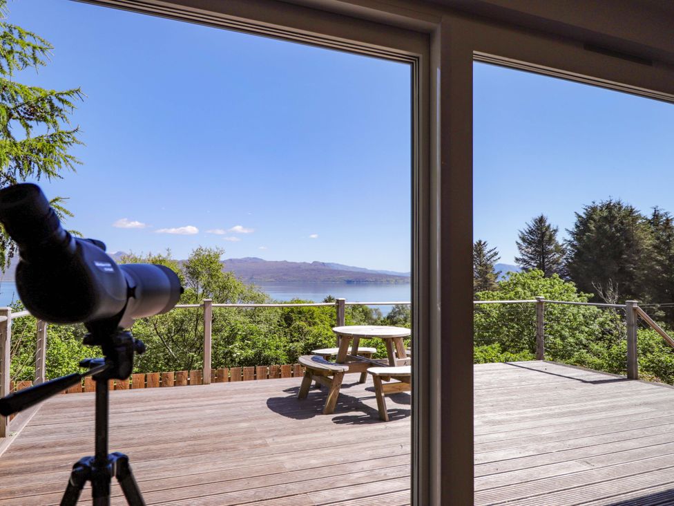 A view from a deck with a telescope and picnic table at The Lookout in Saasaig near Broadford