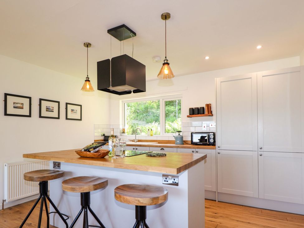 A kitchen with a wooden table and bar stools at The Lookout in Saasaig near Broadford