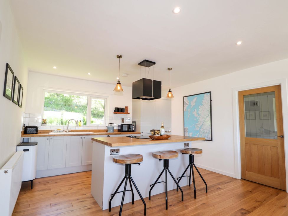 A kitchen with a sink and stools at The Lookout in Saasaig near Broadford