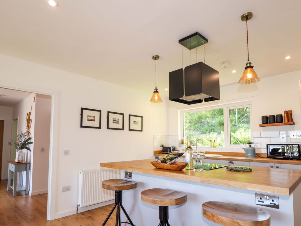A kitchen with a bar island and stools at The Lookout in Saasaig near Broadford