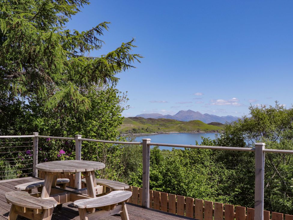 An outdoor seating area with a table and chairs overlooking the water at The Lookout Saasaig near Broadford