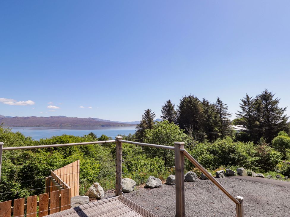 A view of trees and water from a deck at The Lookout in Saasaig near Broadford